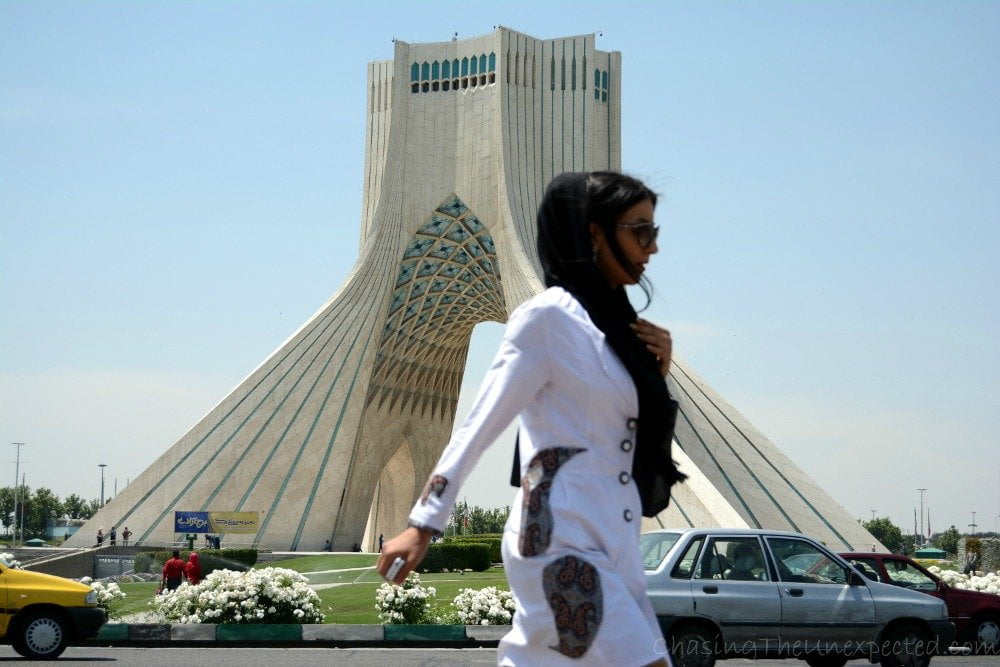 Woman going past Azadi Tower in Tehran